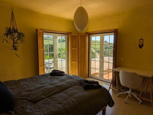 a bedroom with a bed and a desk and windows at Coworksurf - Villa dos Irmãos in Ericeira