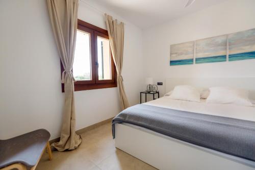 a white bedroom with a bed and a window at Sa Font in Lloret de Vistalegre