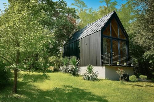 a black barn with a large window and plants at Cabin 16 in Čolakovica Potok