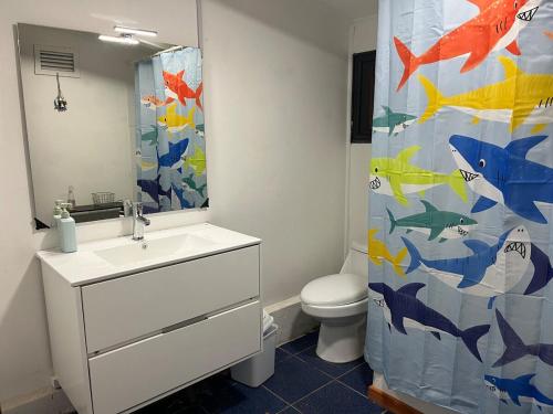 a bathroom with a sink and a shower curtain with fish on it at Maitencillo, amplía y cómoda casa, con piscina y hoy tub in Puchuncaví