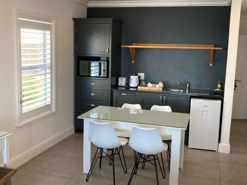 a kitchen with a table and some white chairs at Oceans Drift Guest House & Self Catering in Simonʼs Town