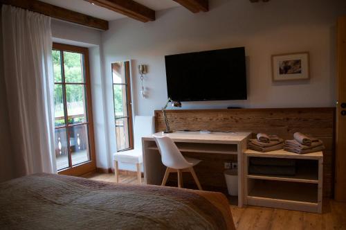 een slaapkamer met een bureau en een televisie aan de muur bij Chalet Fluh in Schindelberg