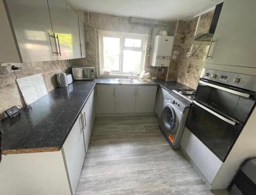 a kitchen with a washer and a sink and a dishwasher at Spacious Double Room By Town Centre in Stevenage