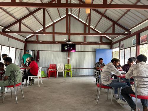 a group of people sitting at tables in a building at River Rock Camps in Jispa