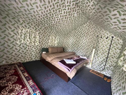 a small bed in a room with a wall at River Rock Camps in Jispa