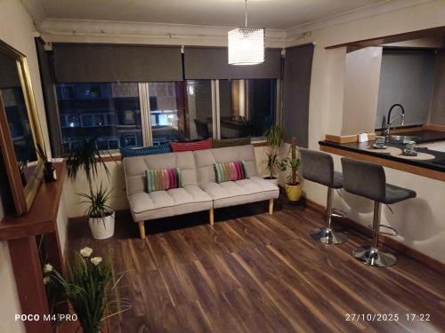 a living room with a couch and a kitchen at Open space studio in Shawlands in Glasgow