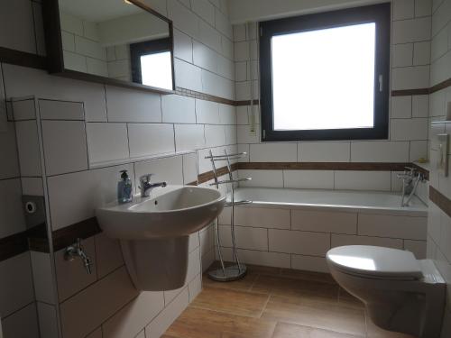 a bathroom with a sink and a toilet and a window at Ferienwohnung Vollmarshausen in Lohfelden