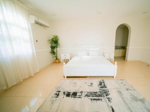 une chambre avec un lit blanc et un tapis dans l'établissement Hideout Farmhouse - By Seven Elements, à Ras al Khaimah