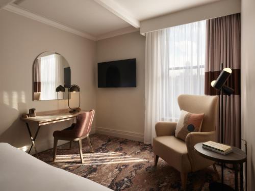 a hotel room with a desk and a chair and a mirror at The Met Hotel Leeds - Newly Refurbished in Leeds