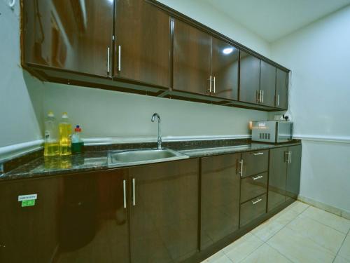 a kitchen with wooden cabinets and a sink at Hideout Farmhouse - By Seven Elements in Ras al Khaimah