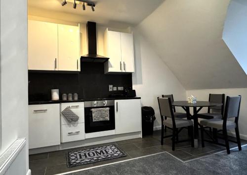 a kitchen with white cabinets and a table with chairs at 81b Queens Road in Watford