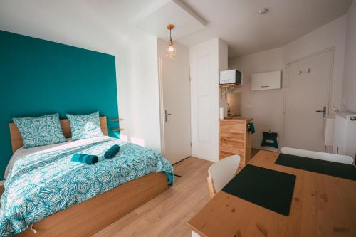 ein Schlafzimmer mit einem Bett mit einer blauen Decke und einem Tisch in der Unterkunft Mon joli studio - Pessac in Pessac