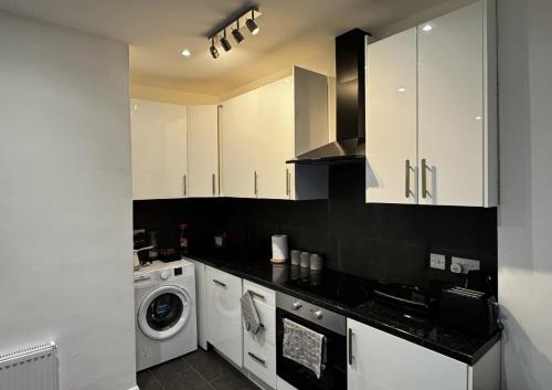 a kitchen with white cabinets and a washing machine at 81b Queens Road in Watford