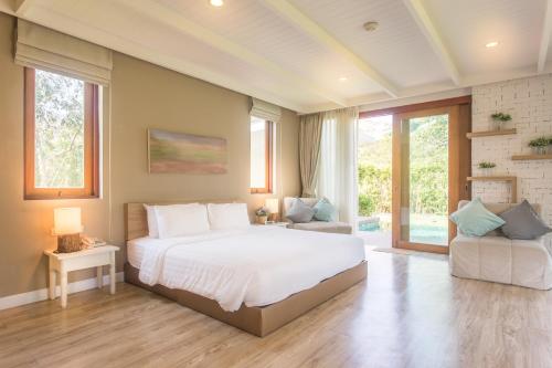 a bedroom with a large white bed and a chair at Prairie Hills Resort in Mu Si