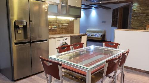 a kitchen with a glass table and a refrigerator at Appartement des Palmiers in Biskra