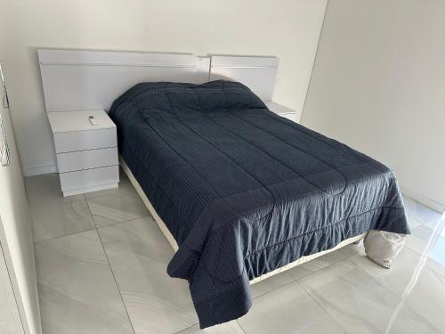 a bed with a black blanket on it in a room at Altamira Surubi-i in Estancia Sarubi