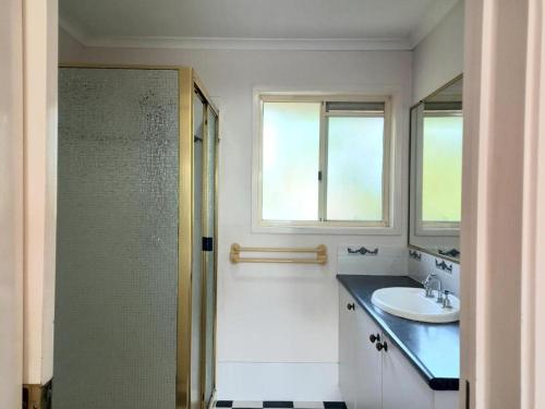 une salle de bain avec un lavabo, un miroir et une douche dans l'établissement 3mins walk to shopping centre city bus airport train station, à Brisbane