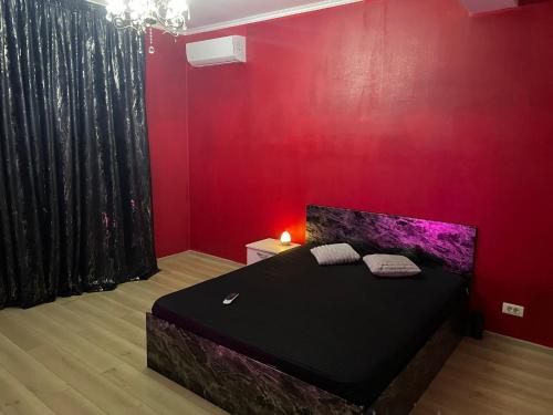 1 dormitorio con cama negra y pared roja en Magical Desire, en Bragadiru