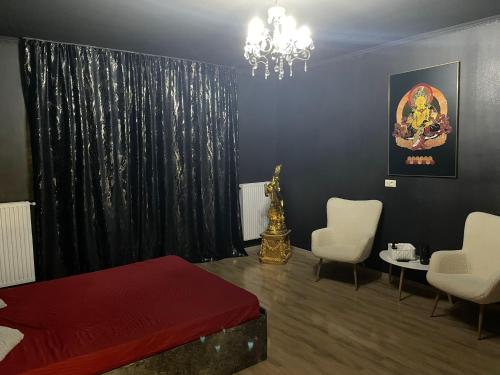 Un dormitorio con una cama roja y dos sillas blancas. en Magical Desire, en Bragadiru