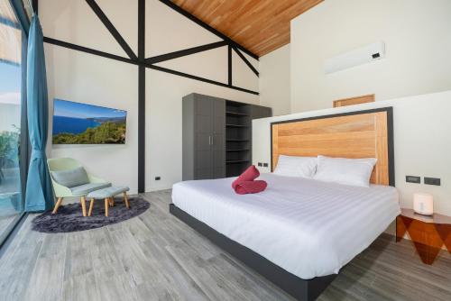 a bedroom with a large bed and a chair at Stylish Eco Villa Sunset Garden 1E with Private Pool near Nai Harn Beach in Ban Saiyuan (1)