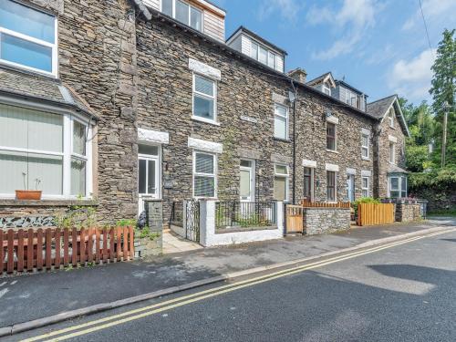 a brick building with a fence on a street at Stanley Cottage in Windermere