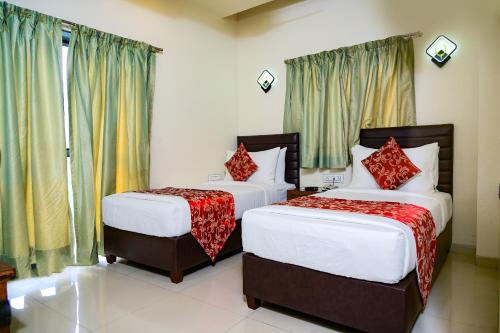two beds in a room with windows and curtains at Masara Biznotel in Chakan