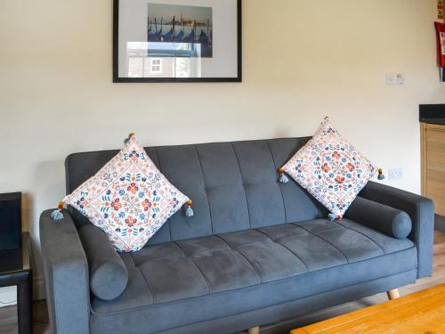 a blue couch in a living room with two pillows on it at Solara Breeze in Reighton