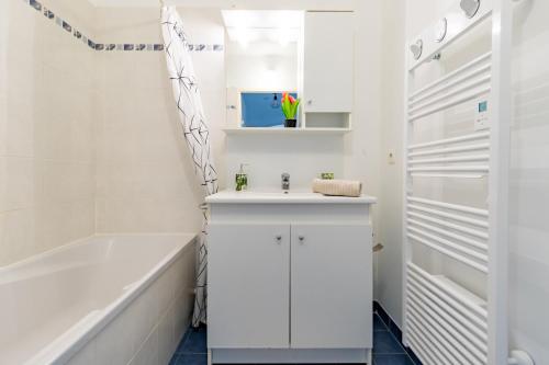 ein weißes Badezimmer mit Waschbecken und Badewanne in der Unterkunft Charming T2 in Frouzins in Frouzins