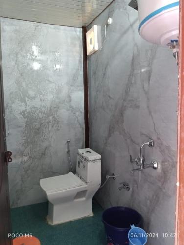 a small bathroom with a toilet and a wall at shree krishna resorts in Pokhri