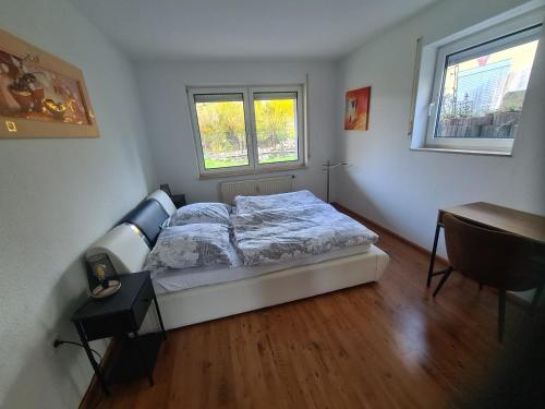 a bedroom with a bed and a desk and two windows at Ferienwohnung Oskar in Gschwend