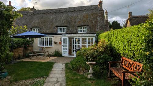 a house with an umbrella and a bench in the yard at 8 Pudding Bag Lane in Exton