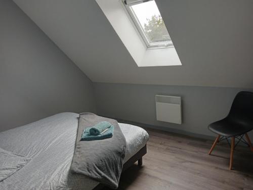 a bedroom with a bed and a chair and a window at La Maison LUDO in Arrest