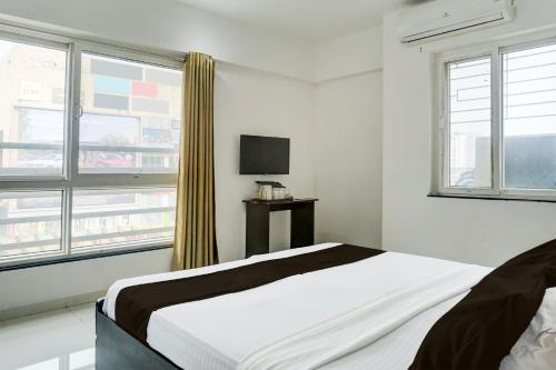 a white bedroom with a bed and a television at Hotel O EKAB Hospitality in Mundhwa