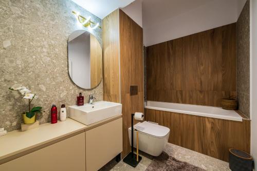 une salle de bain avec un lavabo, des toilettes et un miroir dans l'établissement Metropolitan Spacious Retreat - Balcony and View, à Vatra Mînăstirii Cotroceni