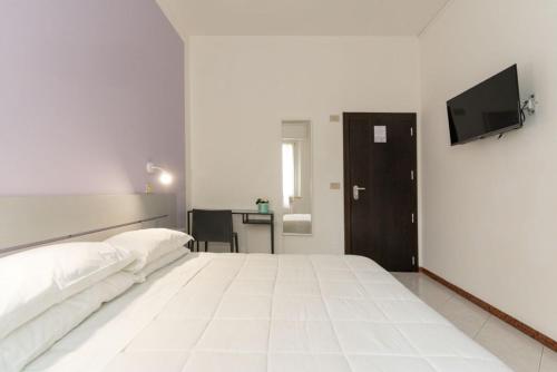a bedroom with a large white bed and a flat screen tv at The Sea Hotel in Rimini