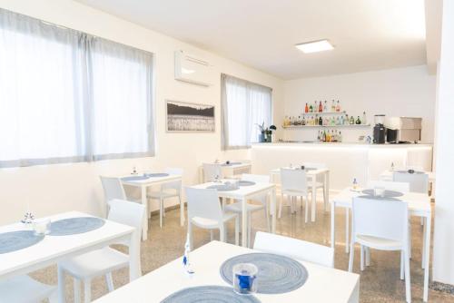 a dining room with white tables and white chairs at The Sea Hotel in Rimini