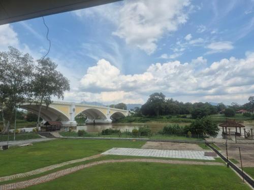 een brug over een rivier met een brug op de achtergrond bij USAS Resort, Kuala Kangsar in Kuala Kangsar