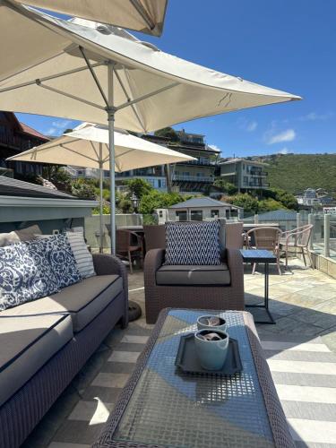 een patio met 2 banken en een parasol bij Woelwaters Beach Villa in Herolds Bay