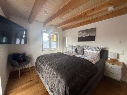 une chambre avec un grand lit et une chaise dans l'établissement Haus Am Faltenbach - Ferienhäuser Alpenglück, à Oberstdorf