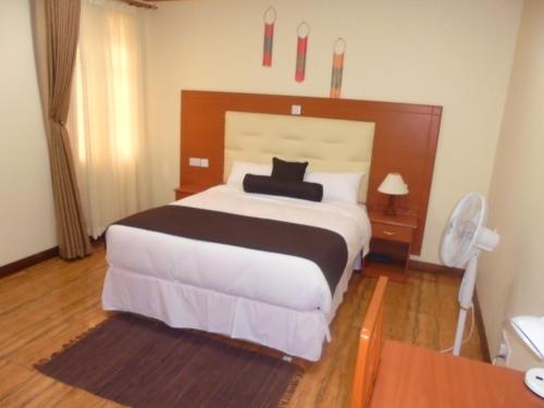 a bedroom with a large bed with a wooden headboard at Villa Leone Boutique Hotel in Nairobi