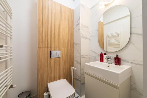 une salle de bains avec un lavabo blanc et un miroir dans l'établissement Panoramic Penthouse Views - Cozy 2BR Retreat, à Vatra Mînăstirii Cotroceni