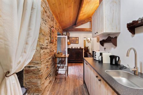 a kitchen with a stone wall and a counter with a sink at Casas da Chica com Piscina, Arouca in Espiunca