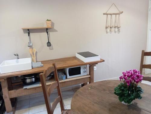 cocina con mesa, fregadero y microondas en Maisonnette cosy 2 chambres, en Freyming-Merlebach