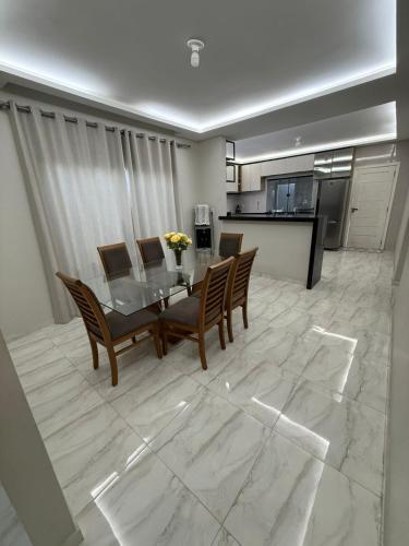 a dining room with a table and chairs and a kitchen at Casa de 4 Quartos - 2 suites in Ananindeua