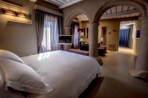 a bedroom with a large white bed and a living room at Uve Rooms & Wine Bar in La Morra