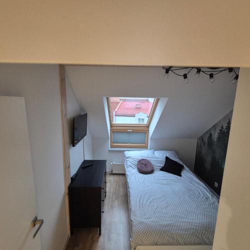 Un dormitorio pequeño con una cama y una ventana. en APATRAMET Królowej Jadwigi 12A, en Giżycko