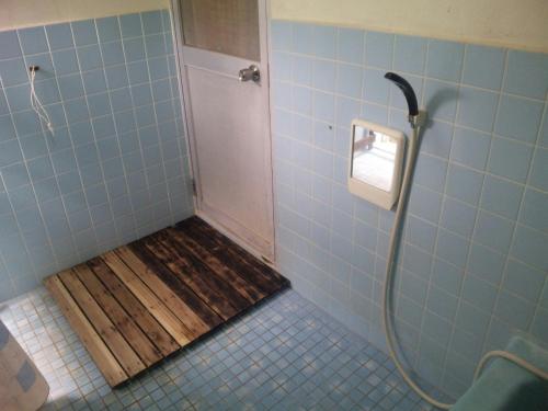 a shower stall with a wooden floor in a bathroom at Okinawa Motobu Guest House in Motobu