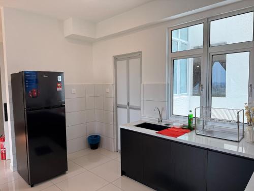 Una cocina con un refrigerador negro y un fregadero. en Self Check in Mirai Kajang 3BR, en Kajang