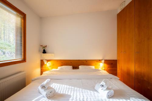 ein Schlafzimmer mit einem Bett mit weißen Laken und einem Fenster in der Unterkunft Rukariutta Apartments in Ruka