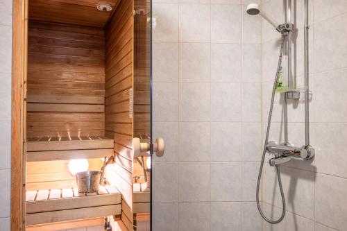eine Dusche im Bad mit Holzwänden und einer Dusche in der Unterkunft Rukariutta Apartments in Ruka